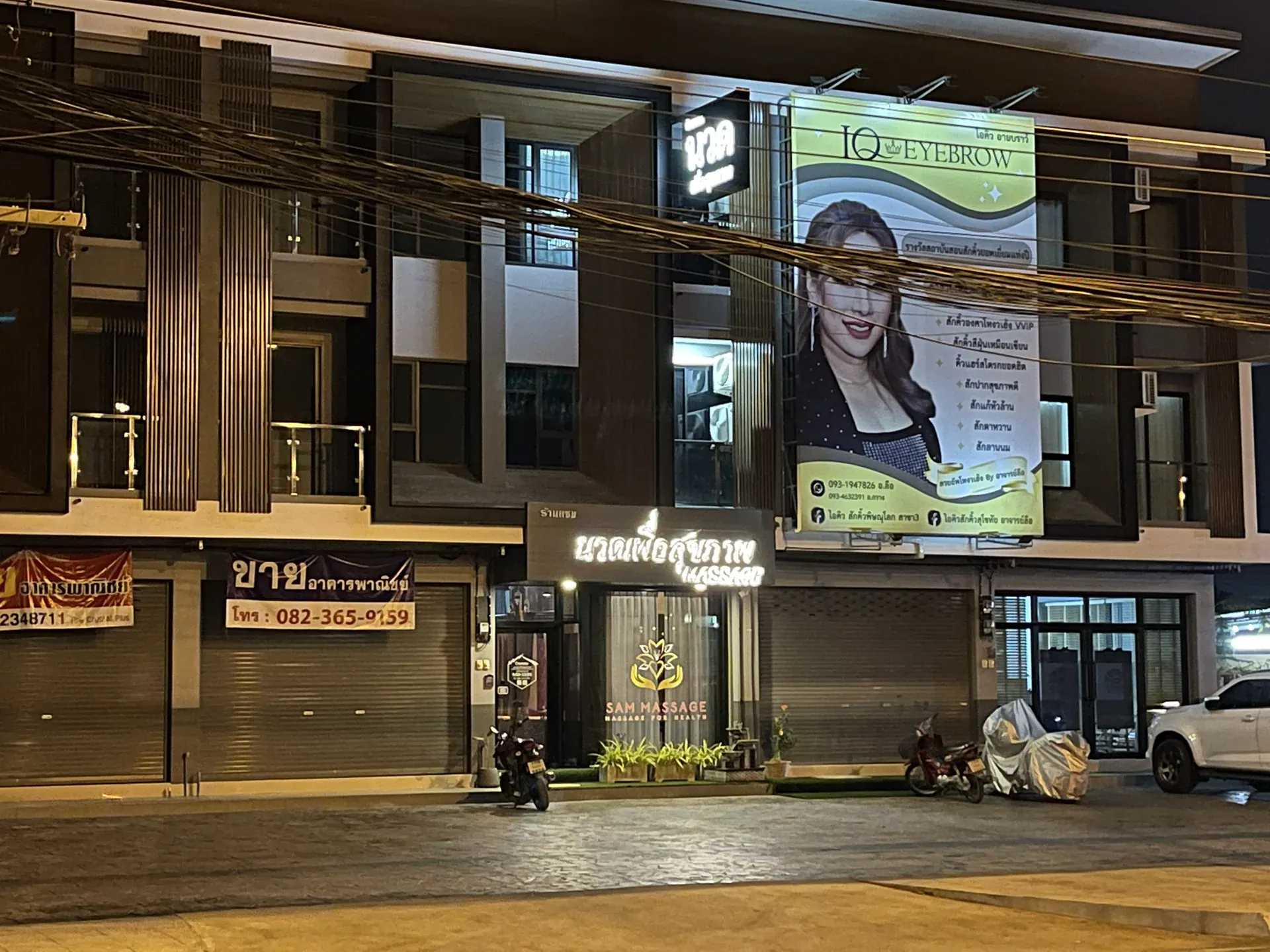 SAM Massage storefront and customer parking area at night